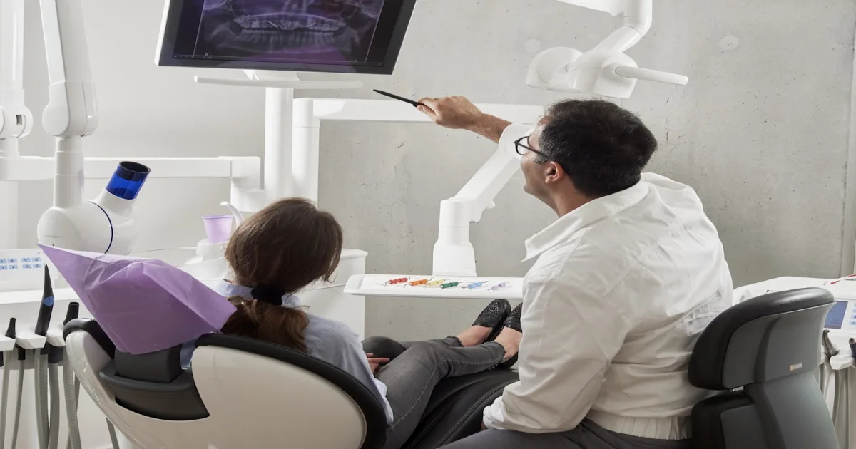 Odontólogo explicando un diagnóstico a una paciente con equipamiento digital de consultorio